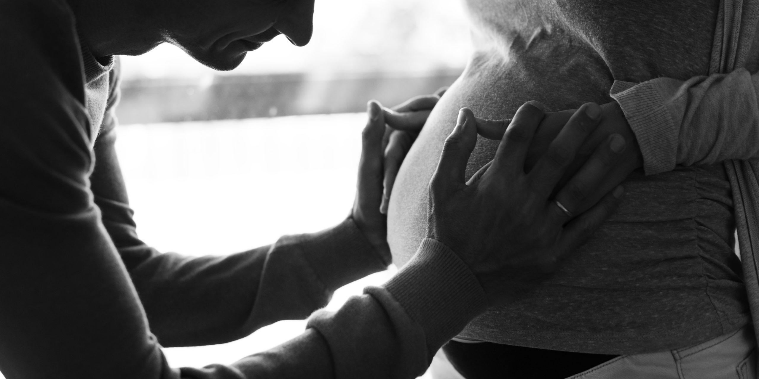 pro-life - para spodziewająca się dziecka. Ojciec trzymający dłonie na brzuchu matki.